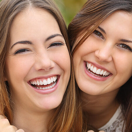 Two women friends laughing with a perfect white teeth Teeth Whitening in Holladay